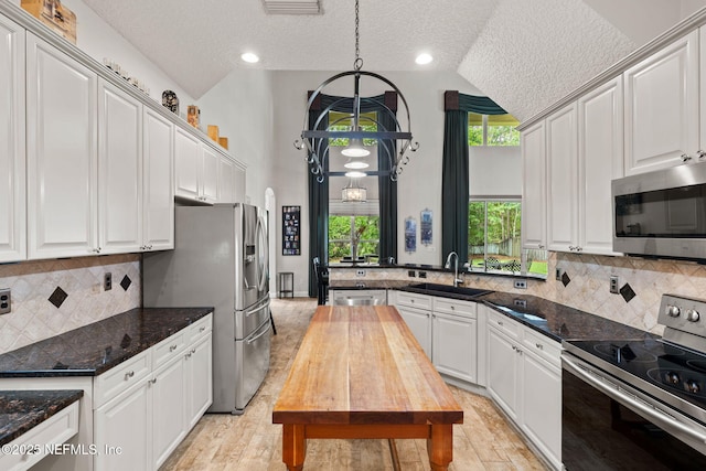 1159 Eastwood Branch Dr, Saint Johns, FL 32259 - kitchen with appliances with stainless steel finishes, a sink, a textured ceiling, white cabinets, and high vaulted ceiling