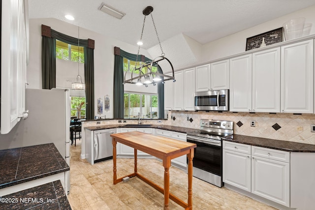 1159 Eastwood Branch Dr, Saint Johns, FL 32259 - kitchen featuring stainless steel appliances, a sink, a chandelier, white cabinetry, and vaulted ceiling