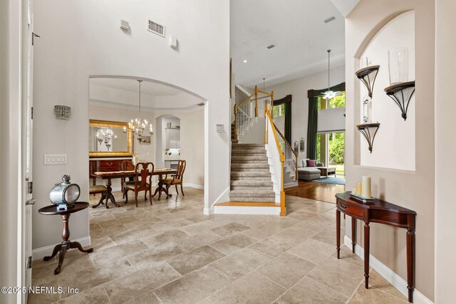 1159 Eastwood Branch Dr, Saint Johns, FL 32259 - foyer entrance with baseboards, stairway, a towering ceiling, arched walkways, and stone tile flooring