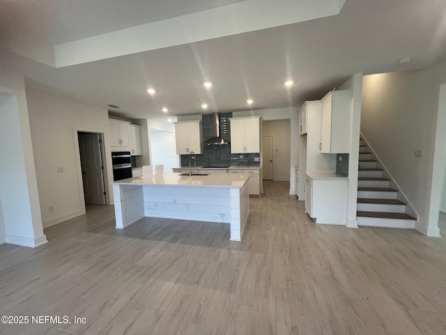 96088 Pirates Bluff Rd, Yulee, FL 32097 - kitchen featuring wall chimney range hood, light wood finished floors, white cabinetry, tasteful backsplash, and recessed lighting