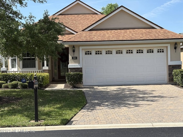 501 N Legacy Trl, Saint Augustine, FL 32092 - view of front facade featuring a shingled roof, stone siding, an attached garage, and decorative driveway
