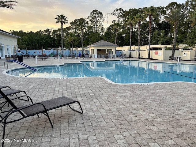 501 N Legacy Trl, Saint Augustine, FL 32092 - pool at dusk featuring a community pool, a patio, and view of wooded area