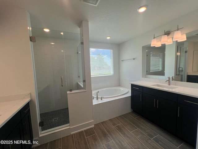 96100 Pirates Bluff Rd, Yulee, FL 32097 - bathroom with two vanities, a stall shower, a garden tub, wood finished floors, and recessed lighting
