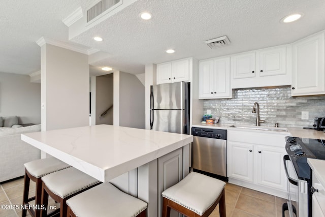 1165 Beach Walker Rd, Fernandina Beach, FL 32034 - kitchen with stainless steel appliances, a sink, light tile patterned floors, a textured ceiling, and a breakfast bar area
