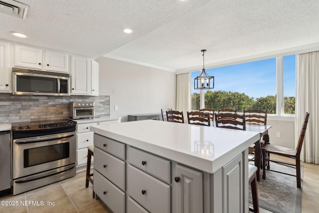 1165 Beach Walker Rd, Fernandina Beach, FL 32034 - kitchen featuring stainless steel appliances, a kitchen breakfast bar, backsplash, gray cabinetry, and a textured ceiling