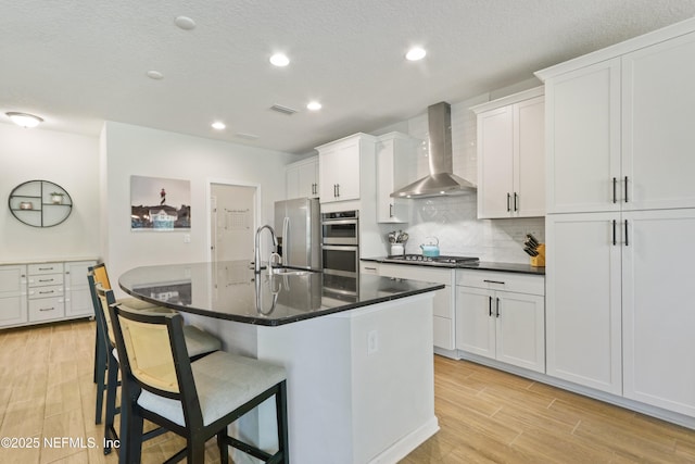 264 Windermere Way, Saint Augustine, FL 32095 - kitchen with wall chimney range hood, stainless steel appliances, light wood-style flooring, dark countertops, and recessed lighting
