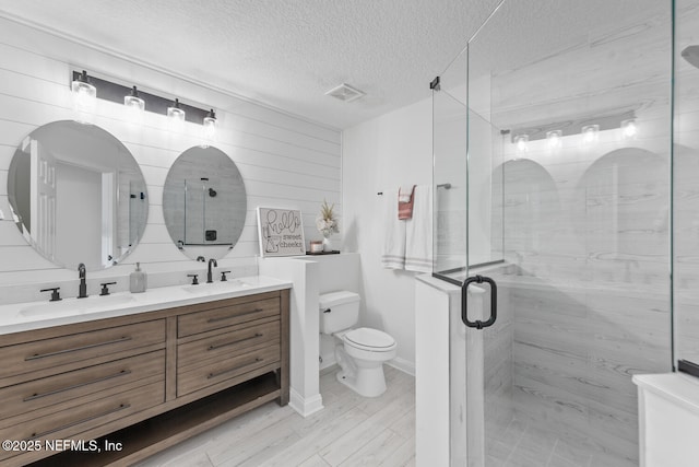 6547 Burnham Cir, Ponte Vedra Beach, FL 32082 - bathroom featuring toilet, double vanity, a textured ceiling, a shower stall, and wood finished floors