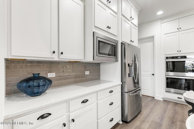 638 Windley Dr, Saint Augustine, FL 32092 - kitchen with stainless steel appliances, white cabinetry, backsplash, light wood finished floors, and light stone countertops