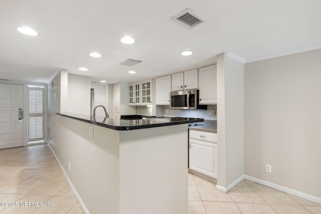 3036 Sea Marsh Rd, Fernandina Beach, FL 32034 - kitchen with stainless steel microwave, light tile patterned floors, white cabinets, glass insert cabinets, and crown molding