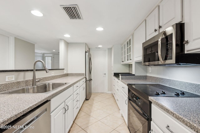 3036 Sea Marsh Rd, Fernandina Beach, FL 32034 - kitchen with stainless steel appliances, a sink, white cabinets, recessed lighting, and light tile patterned floors