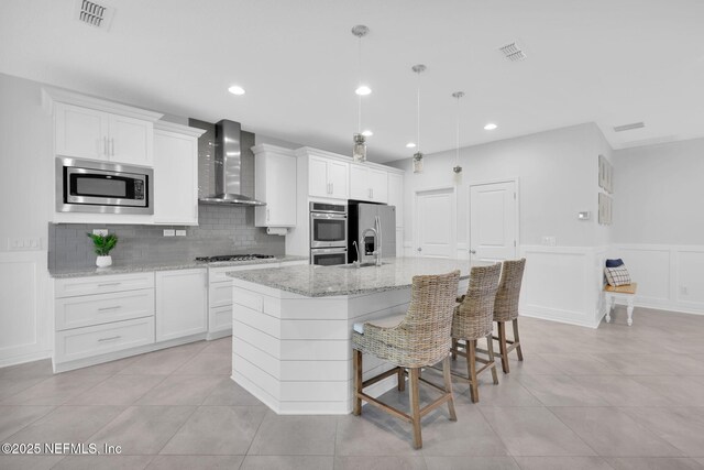 25 Carnauba Way, Jacksonville, FL 32081 - kitchen with wall chimney exhaust hood, stainless steel appliances, an island with sink, tasteful backsplash, and white cabinets