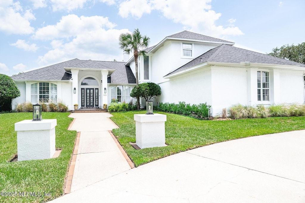 426 Marsh Point Cir, Saint Augustine Beach, FL 32080 - view of front of house with stucco siding, a front yard, and a shingled roof