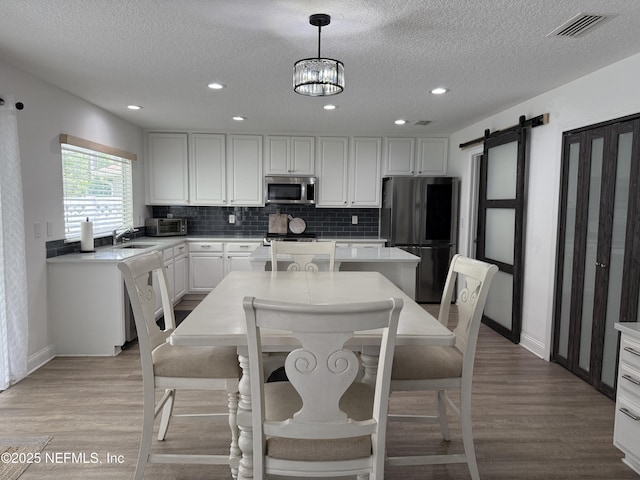 305 Carriage Hill Ct, Saint Johns, FL 32259 - kitchen featuring freestanding refrigerator, stainless steel microwave, a textured ceiling, a barn door, and backsplash
