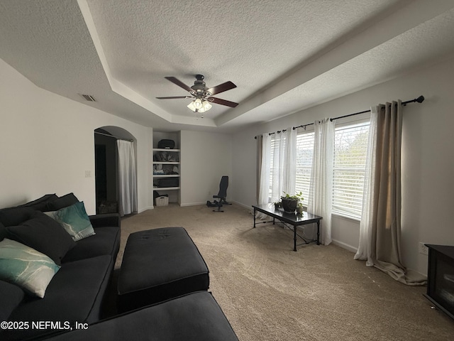305 Carriage Hill Ct, Saint Johns, FL 32259 - living room with a textured ceiling, light carpet, arched walkways, a tray ceiling, and ceiling fan