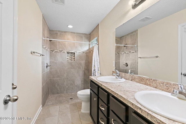4116 Adirolf Rd, Jacksonville, FL 32207 - bathroom featuring double vanity, a tile shower, toilet, tile patterned flooring, and a textured ceiling