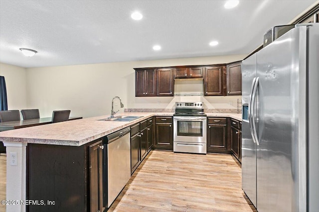 4116 Adirolf Rd, Jacksonville, FL 32207 - kitchen featuring appliances with stainless steel finishes, a sink, light wood-type flooring, dark brown cabinetry, and light countertops