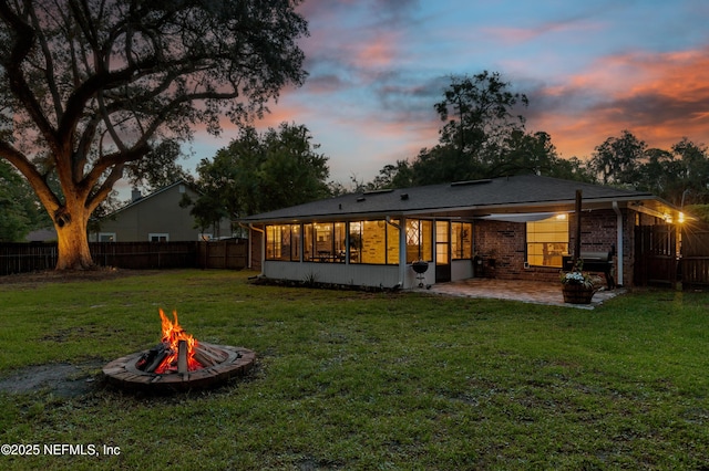 884 Live Oak Ln, Fleming Island, FL 32003 - back of property at dusk with an outdoor fire pit, a patio, a fenced backyard, and a sunroom