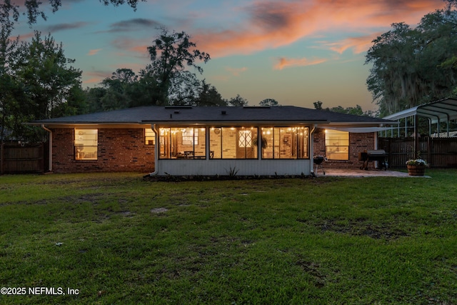 884 Live Oak Ln, Fleming Island, FL 32003 - back of property at dusk featuring brick siding, a patio area, and a detached carport
