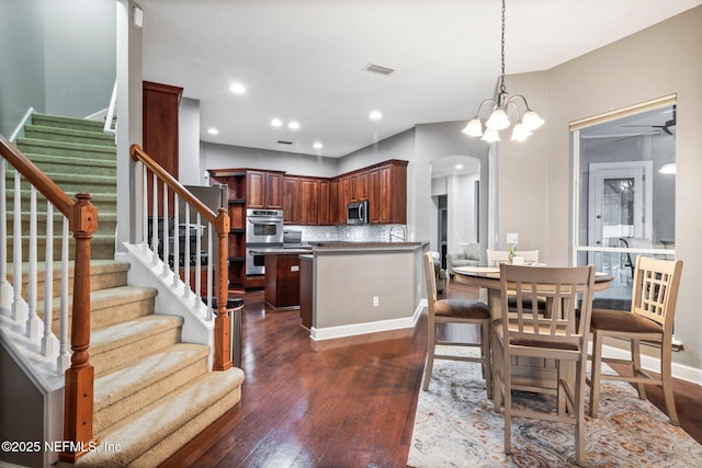 3746 Cardinal Oaks Cir, Orange Park, FL 32065 - dining room featuring dark wood-style flooring, stairway, arched walkways, ceiling fan, and baseboards