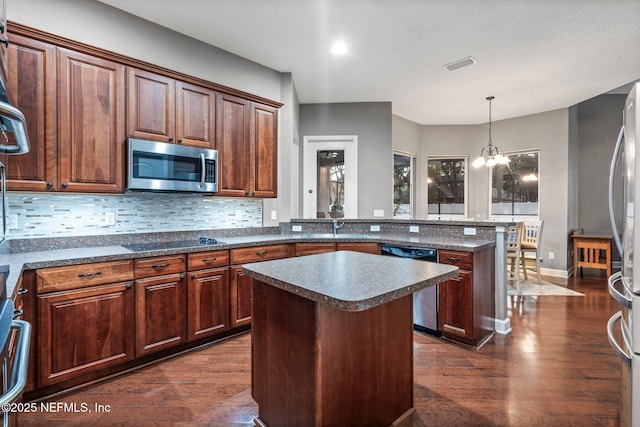 3746 Cardinal Oaks Cir, Orange Park, FL 32065 - kitchen with stainless steel appliances, dark wood finished floors, dark countertops, a peninsula, and tasteful backsplash