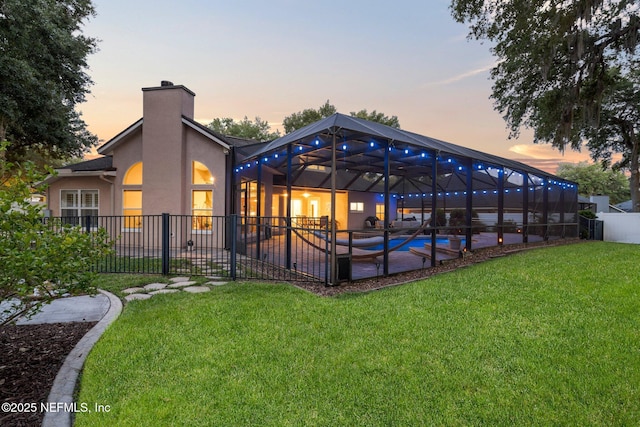 3746 Cardinal Oaks Cir, Orange Park, FL 32065 - back of house at dusk featuring a patio area, a chimney, stucco siding, and glass enclosure
