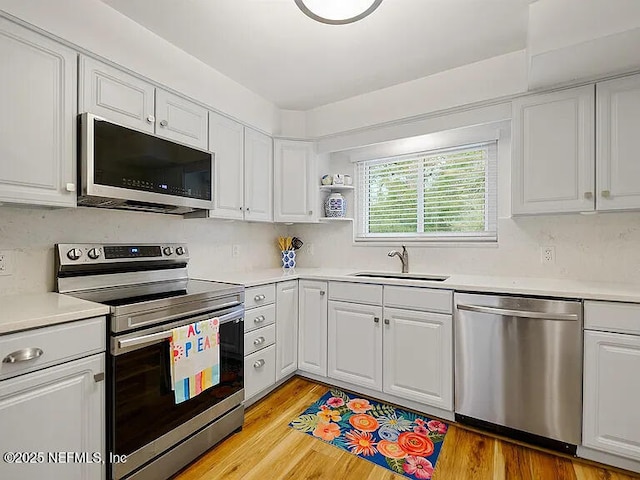 2700 Mizell Ave Unit 402B, Fernandina Beach, FL 32034 - kitchen with appliances with stainless steel finishes, a sink, white cabinets, light countertops, and light wood-style floors