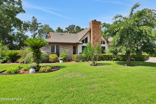 5604 Swamp Fox Rd, Jacksonville, FL 32210 - view of front of home with a shingled roof, a front lawn, a chimney, and brick siding