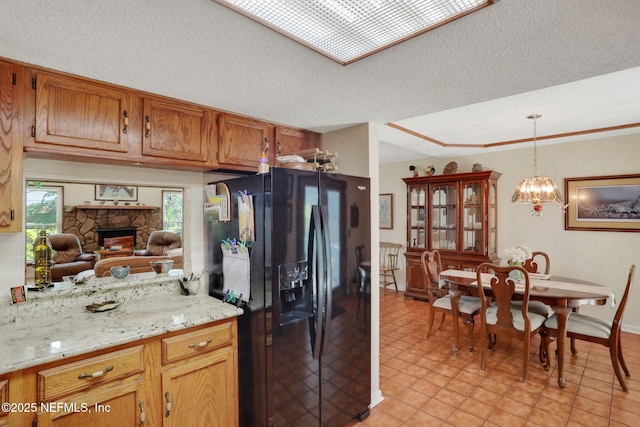 5604 Swamp Fox Rd, Jacksonville, FL 32210 - kitchen featuring black refrigerator with ice dispenser, a fireplace, pendant lighting, brown cabinetry, and baseboards