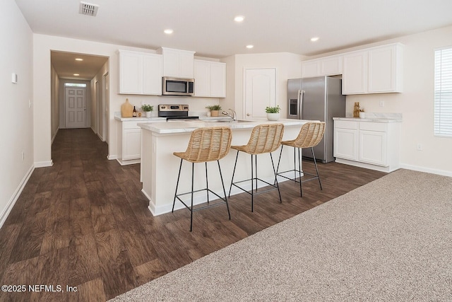 2719 Oak Stream Dr, Green Cove Springs, FL 32043 - kitchen featuring stainless steel appliances, a sink, an island with sink, dark wood finished floors, and white cabinetry