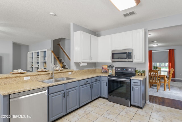 521 Cedar Arbor Ct, Saint Augustine, FL 32084 - kitchen with stainless steel appliances, a sink, white cabinets, a peninsula, and a textured ceiling
