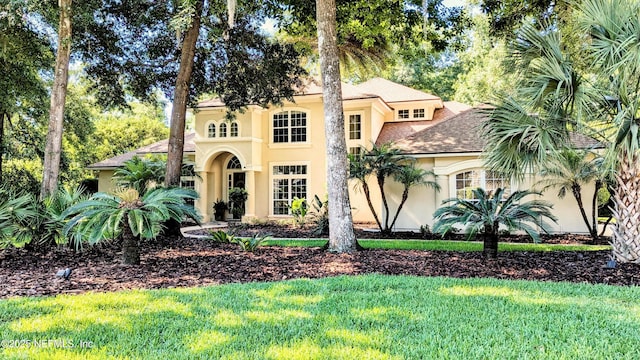 2708 Shade Tree Dr, Fleming Island, FL 32003 - mediterranean / spanish house with stucco siding, a front lawn, and roof with shingles