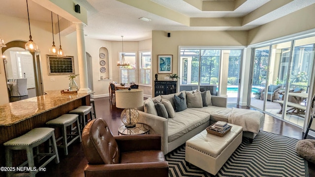 2708 Shade Tree Dr, Fleming Island, FL 32003 - living room with arched walkways, dark wood-style flooring, a chandelier, and baseboards