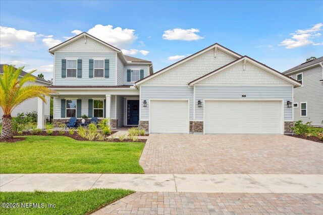 199 Ranch Land Cir, Saint Johns, FL 32259 - craftsman inspired home with a garage, covered porch, stone siding, a front lawn, and decorative driveway