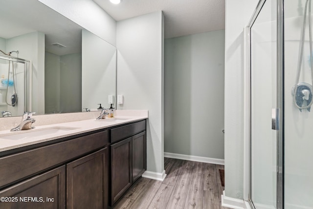 8552 Lake George Cir W, Macclenny, FL 32063 - bathroom featuring a shower stall, wood finished floors, double vanity, and baseboards