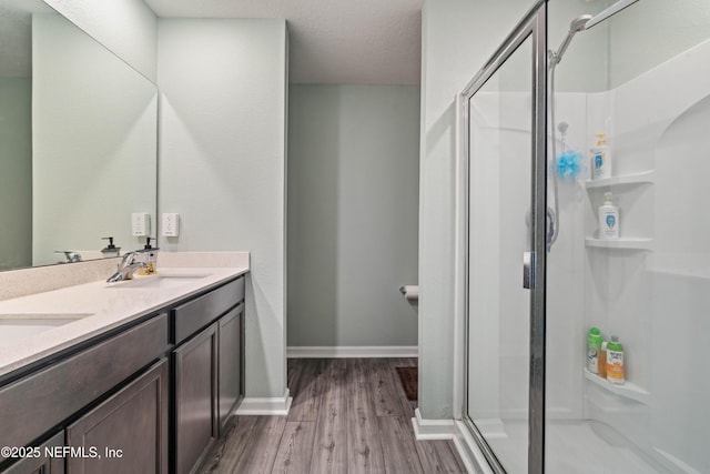 8552 Lake George Cir W, Macclenny, FL 32063 - bathroom featuring wood finished floors, a shower stall, double vanity, and baseboards