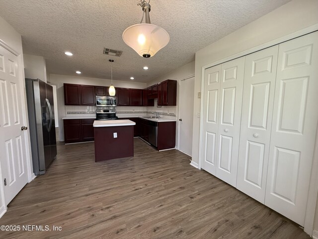 9205 Camshire Dr, Jacksonville, FL 32244 - kitchen featuring stainless steel appliances, a kitchen island, light countertops, a sink, and dark wood-type flooring