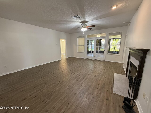 9205 Camshire Dr, Jacksonville, FL 32244 - unfurnished living room featuring ceiling fan, a textured ceiling, a fireplace with flush hearth, dark wood-style floors, and baseboards