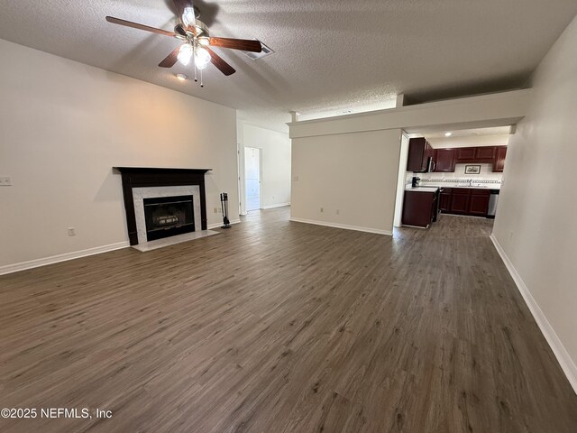 9205 Camshire Dr, Jacksonville, FL 32244 - unfurnished living room with ceiling fan, dark wood-style floors, a textured ceiling, a fireplace with flush hearth, and baseboards