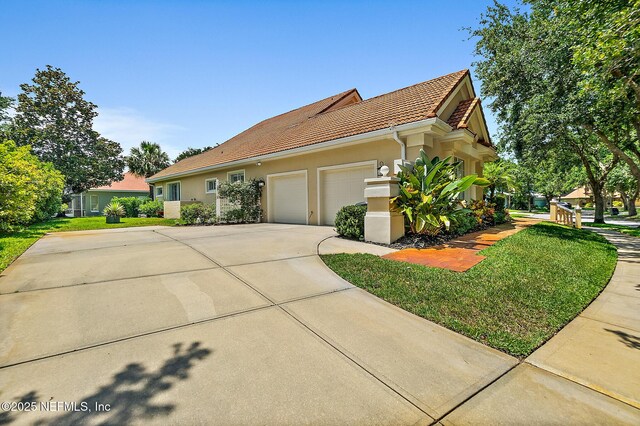 5 Augusta Trl, Palm Coast, FL 32137 - view of side of property with a tiled roof, concrete driveway, an attached garage, stucco siding, and a yard