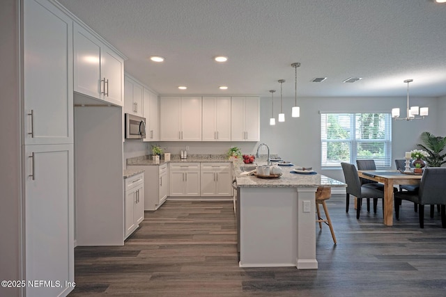 12252 Lyons St, Jacksonville, FL 32224 - kitchen with stainless steel microwave, dark wood-style flooring, recessed lighting, white cabinets, and a textured ceiling
