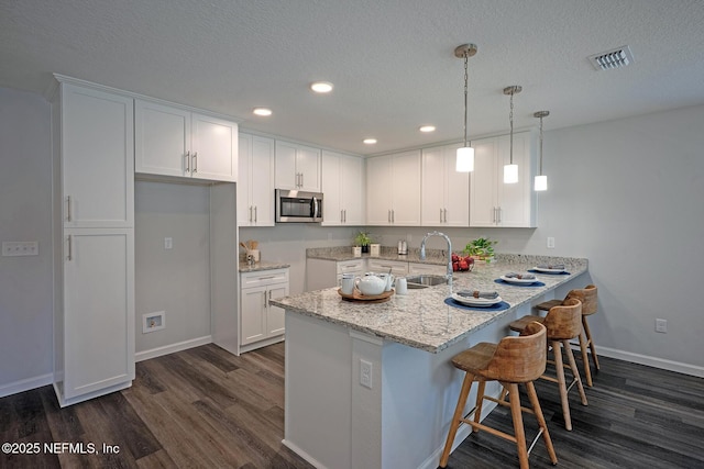 12252 Lyons St, Jacksonville, FL 32224 - kitchen featuring stainless steel microwave, a sink, dark wood finished floors, a peninsula, and recessed lighting