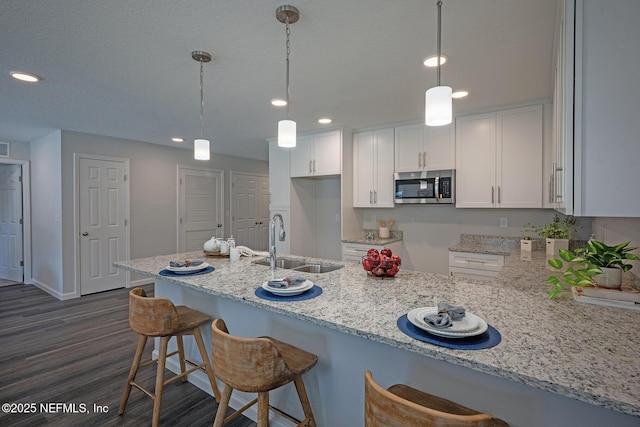 12252 Lyons St, Jacksonville, FL 32224 - kitchen featuring stainless steel microwave, a sink, white cabinets, dark wood finished floors, and recessed lighting