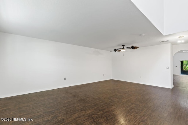 65074 Mossy Creek Ln, Yulee, FL 32097 - empty room featuring arched walkways, dark wood-type flooring, a ceiling fan, and baseboards