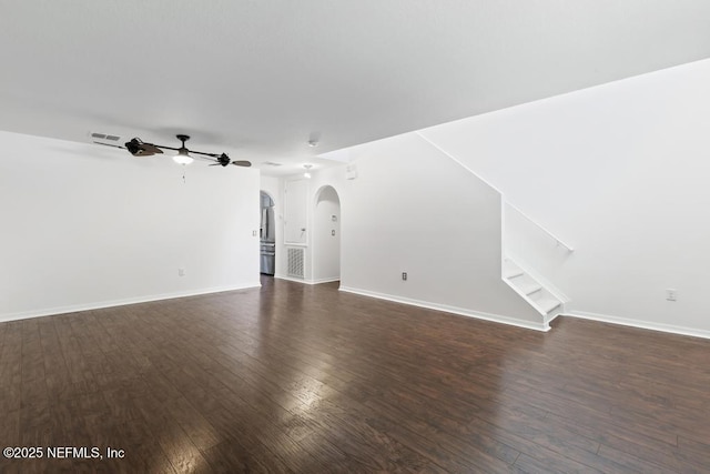 65074 Mossy Creek Ln, Yulee, FL 32097 - unfurnished living room featuring arched walkways, ceiling fan, dark wood-style flooring, stairs, and baseboards