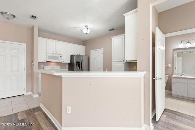 11251 Campfield Dr Unit 4107, Jacksonville, FL 32256 - kitchen with white microwave, stainless steel refrigerator with ice dispenser, light wood-style floors, a peninsula, and white cabinets