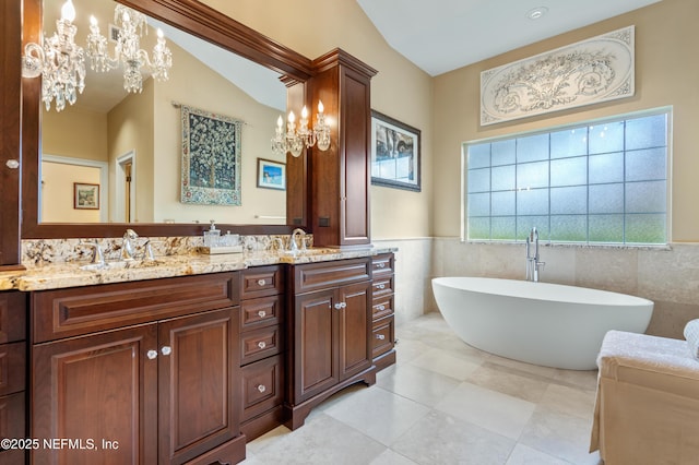 8 Rue Renoir, Palm Coast, FL 32137 - bathroom with a chandelier, double vanity, tile walls, a soaking tub, and wainscoting