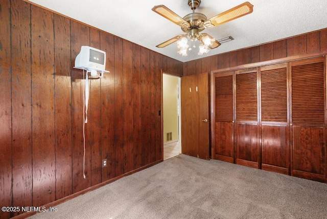 5342 Hickson Rd, Jacksonville, FL 32207 - unfurnished bedroom with carpet, wood walls, a closet, and a ceiling fan