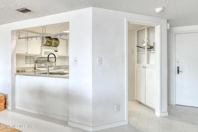 3115 Harbor Dr, Saint Augustine, FL 32084 - kitchen featuring a textured ceiling, light countertops, white microwave, light tile patterned floors, and range