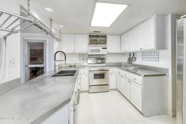 3115 Harbor Dr, Saint Augustine, FL 32084 - kitchen featuring stainless steel range oven, white microwave, a sink, white cabinets, and a textured ceiling