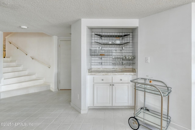 3115 Harbor Dr, Saint Augustine, FL 32084 - bar area with light tile patterned flooring, a textured ceiling, stairs, and baseboards